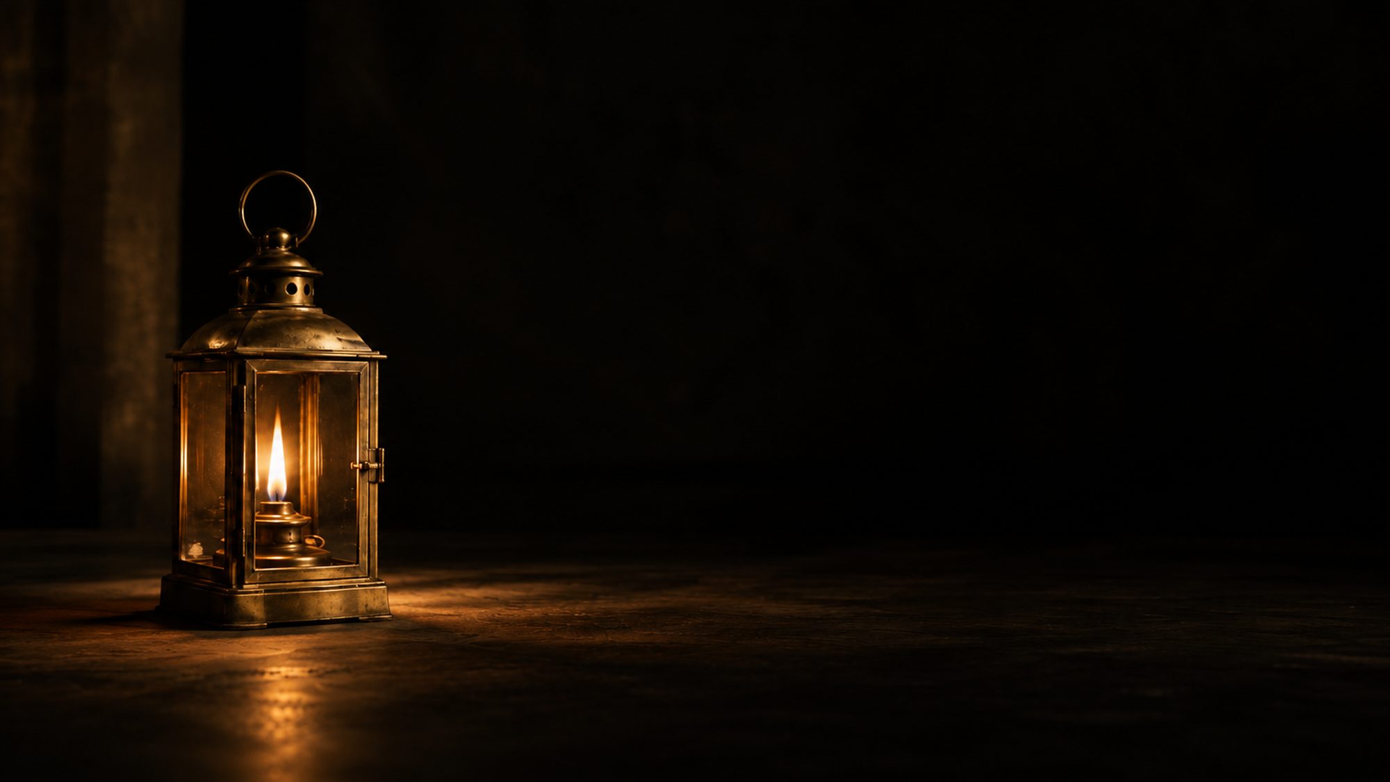 A brass lantern glowing with a small flame in a dark room