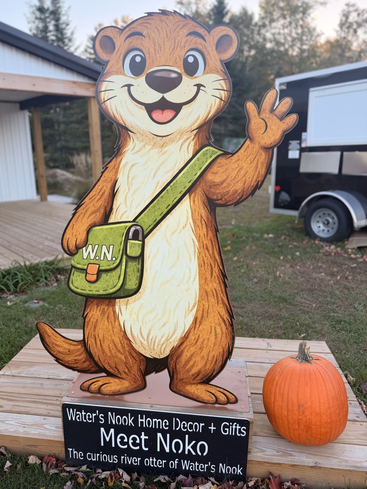 The Meet Noko sign at Water's Nook: a life-size Noko the otter waving, with his green W.N. satchel